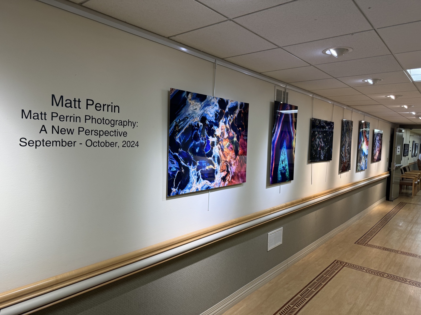 Photographs displayed along a gallery wall beside signage for Matt Perrin Photography: A New Perspective, September–October 2024.